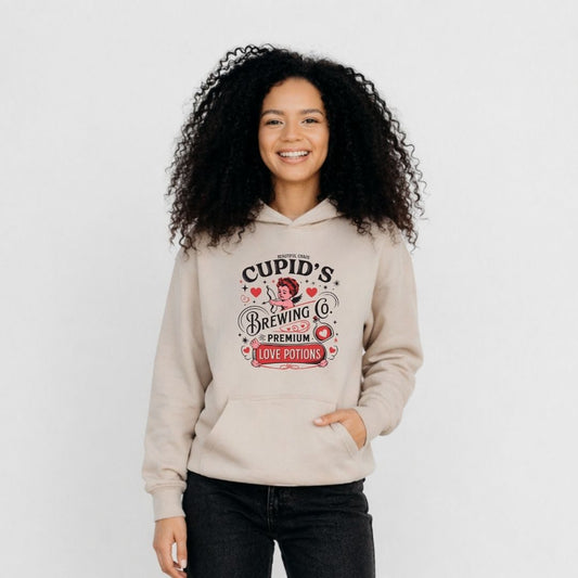 Woman wearing a sand beige hoodie with 'Beautiful Chaos Cupid's Brewing Co' design on a white background