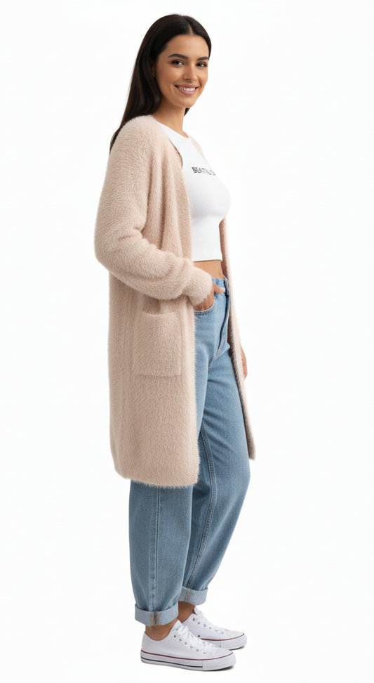 Woman wearing a long beige cardigan, white crop top, and blue jeans on a white background