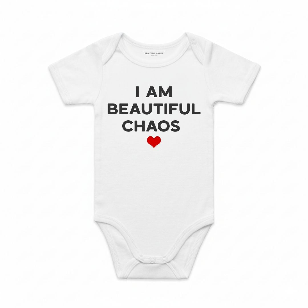 White baby onesie with 'I AM BEAUTIFUL CHAOS' text and a red heart on a white background